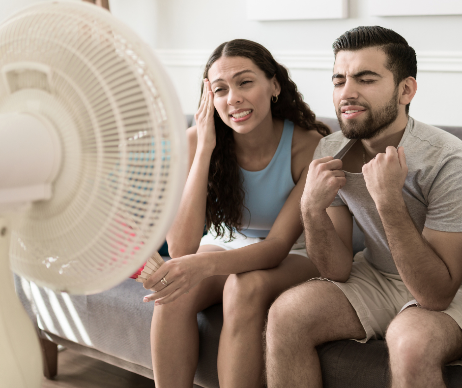 Frustrated couple sitting by fan due to broken air conditioner blowing warm air in Salem, OR